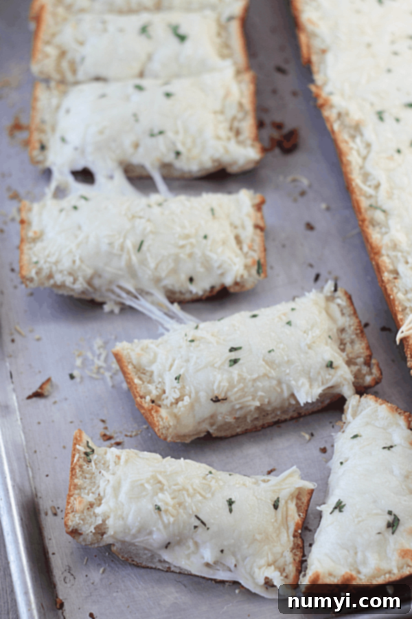 Mouthwatering Cheesy Garlic Bread 2 Freshly baked Cheesy Garlic French Bread slices on a cutting board, garnished with parsley