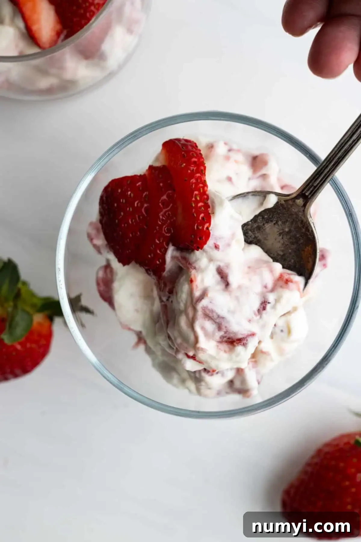 Overhead view of a vibrant Strawberry Rhubarb Fool in an elegant glass serving bowl, garnished with fresh fruit. 