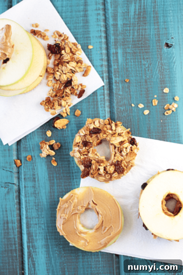 various donut shaped apple slices with peanut butter and granola on top