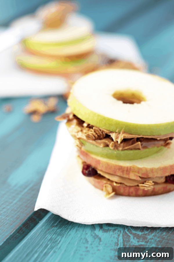apple and peanut butter granola sandwiches on a blue wood surface