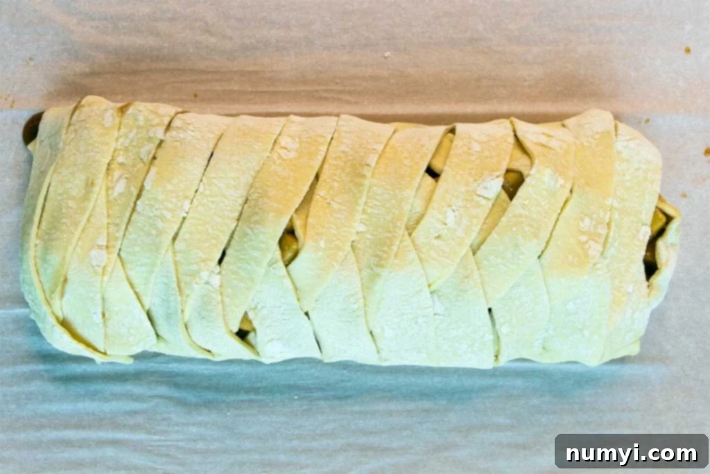 Flaky Apple Strudel Delight 4 Unbaked braided puff pastry strudel on a baking sheet, ready for the oven.