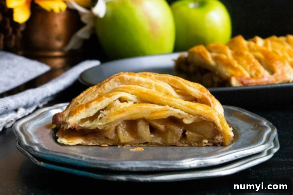 Flaky Apple Strudel Delight 7 A slice of warm apple strudel on a silver plate, revealing the apple filling.