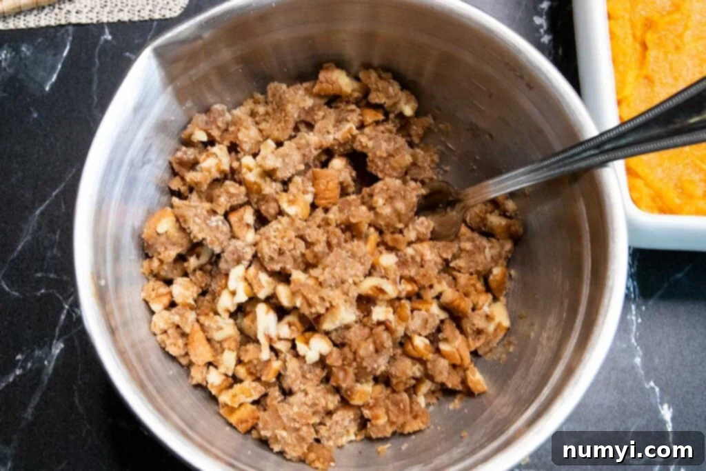Pecan streusel topping mixture in a metal mixing bowl, ready to be frozen.