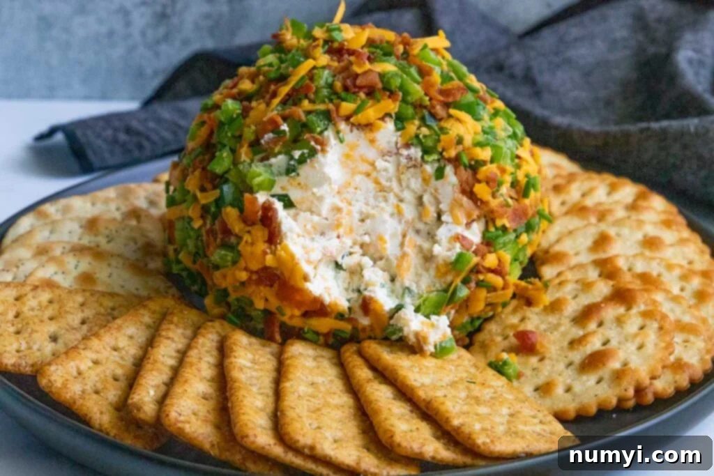 A delicious Jalapeno Popper Cheese Ball, beautifully coated with bacon and jalapenos, served on a black plate with an assortment of crackers.
