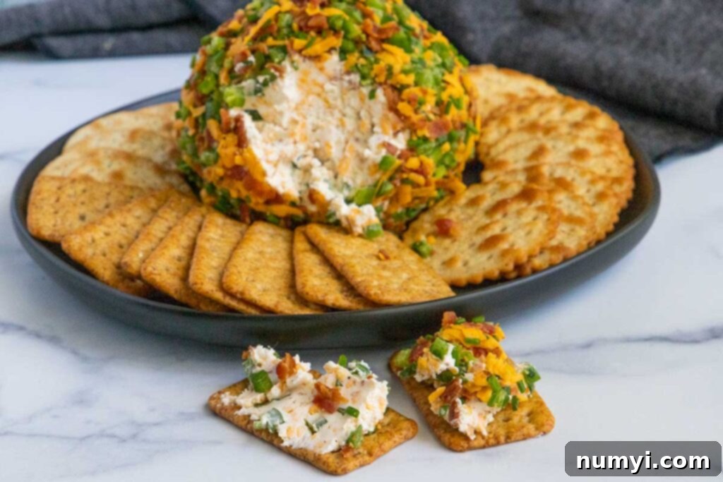 A closer look at the delicious Jalapeno Popper Cheese Ball with a rich topping of bacon, cheddar, and jalapenos, ready to be served with crackers on a dark plate.