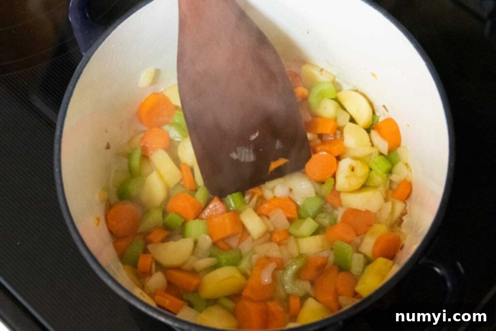 Rustic Root Medley 6 Chopped vegetables, including carrots, onions, and parsnips, cooking in a large pot on the stove.