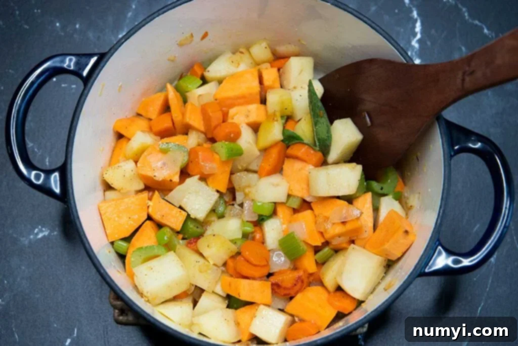 Rustic Root Medley 7 Peeled and chopped potatoes being added to a pot of cooking vegetables.