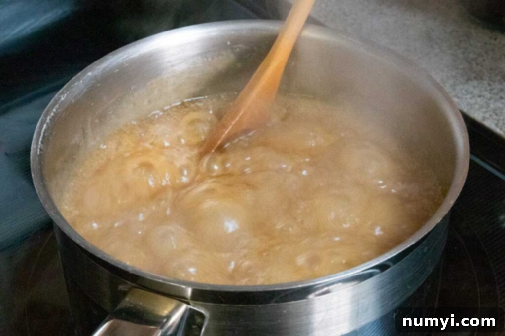 Fudge mixture boiling vigorously in a saucepan on the stove.