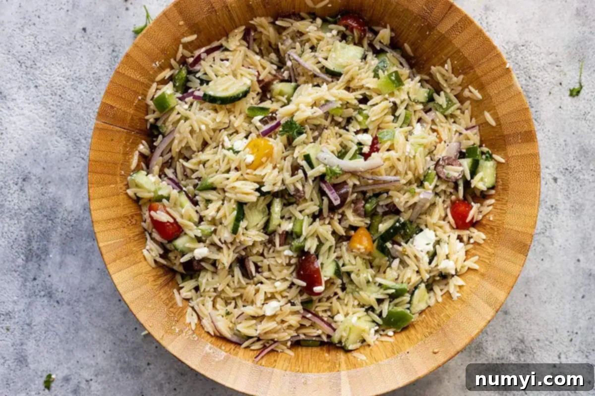 Overhead view of the fully combined Mediterranean orzo pasta salad, showing a colorful mix of ingredients.