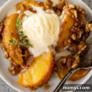 Overhead view of peach crisp on a white plate with ice cream slowly melting into the crisp.