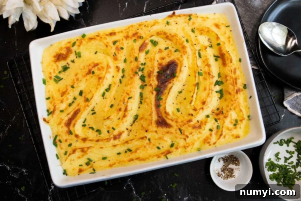 Whipped potatoes in a casserole dish, garnished with fresh herbs.