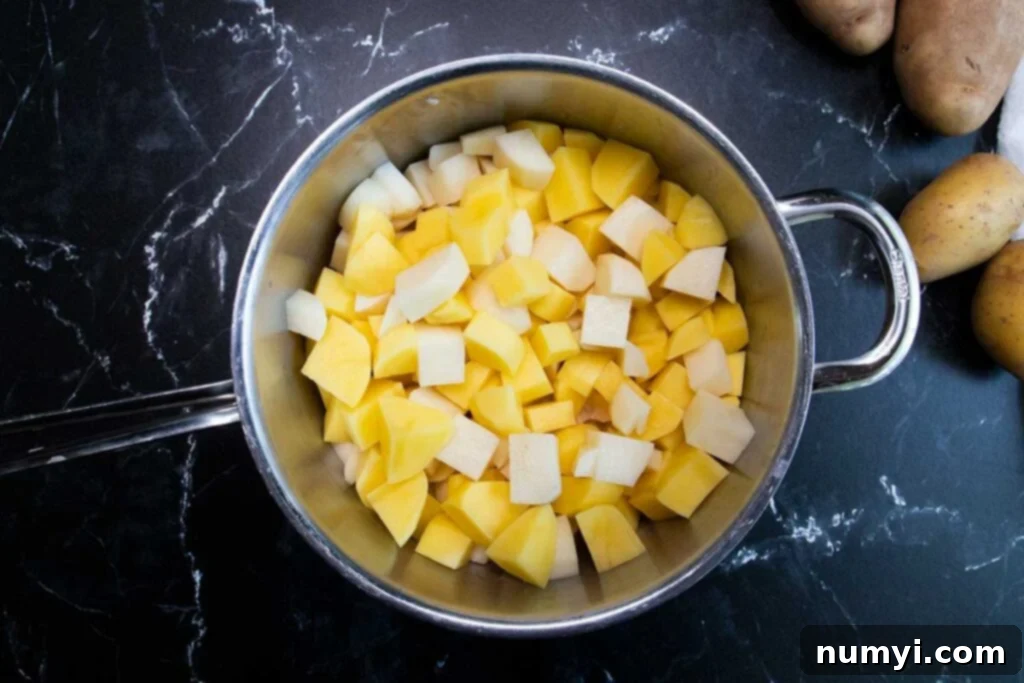 Cubed potatoes boiling in a large pot, with salt added to the water.