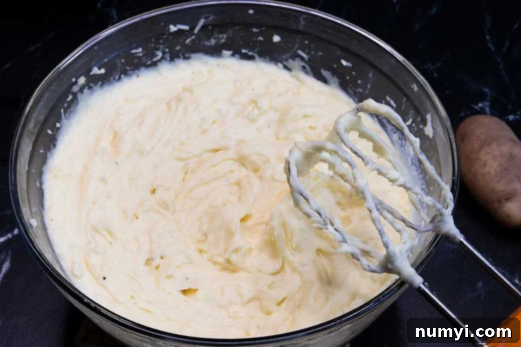 Creamy whipped potatoes in a glass mixing bowl, perfectly smooth.