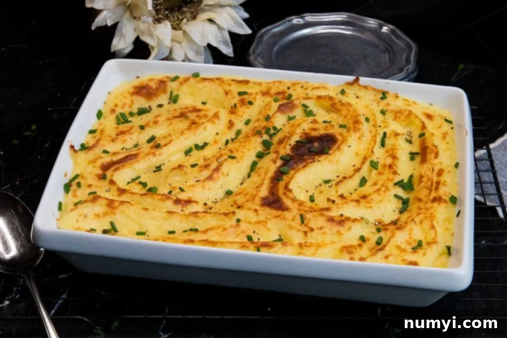 Whipped potatoes in a white casserole dish garnished with chopped chives, ready to be served.