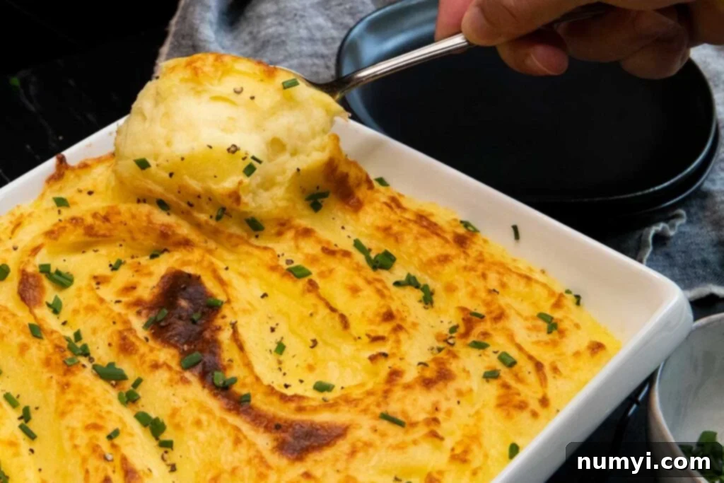 Serving a spoonful of silky smooth whipped potatoes from the dish.
