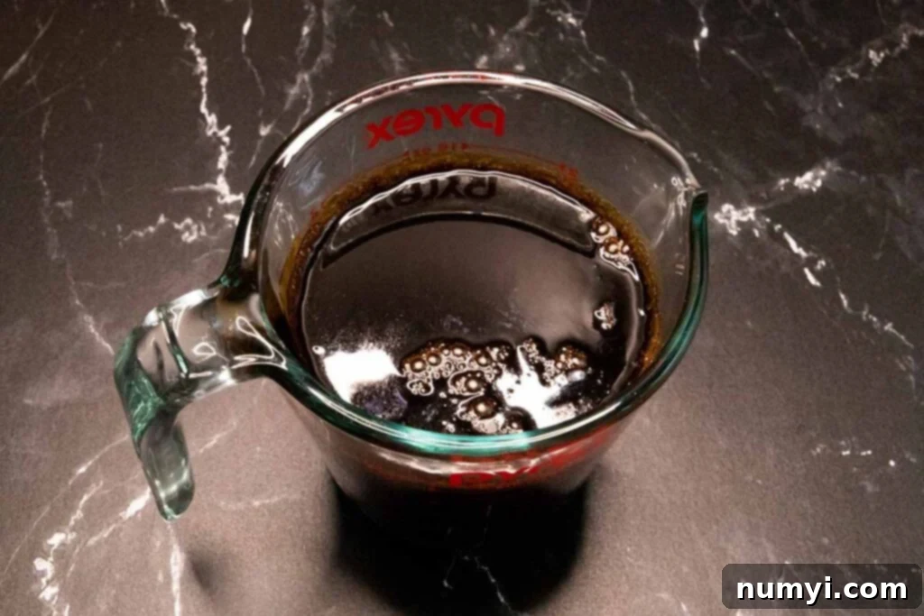 Boiled stout and molasses in a glass measuring cup.