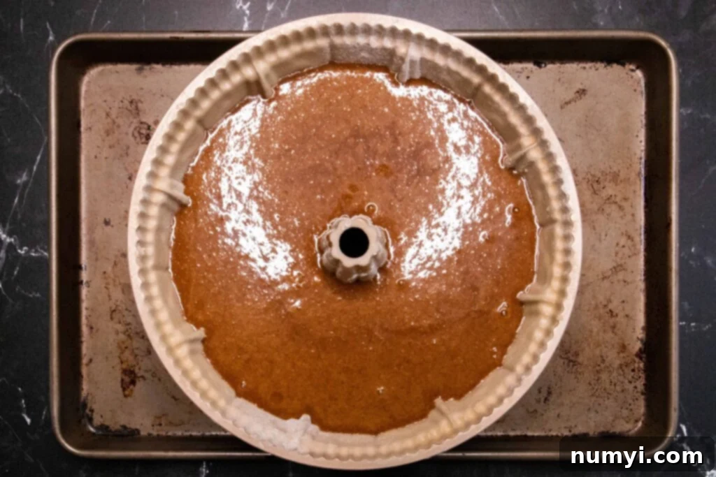 Gingerbread batter in bundt pan on a baking sheet.