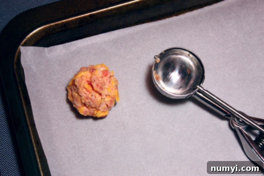 One sausage ball formed on a parchment lined baking sheet.