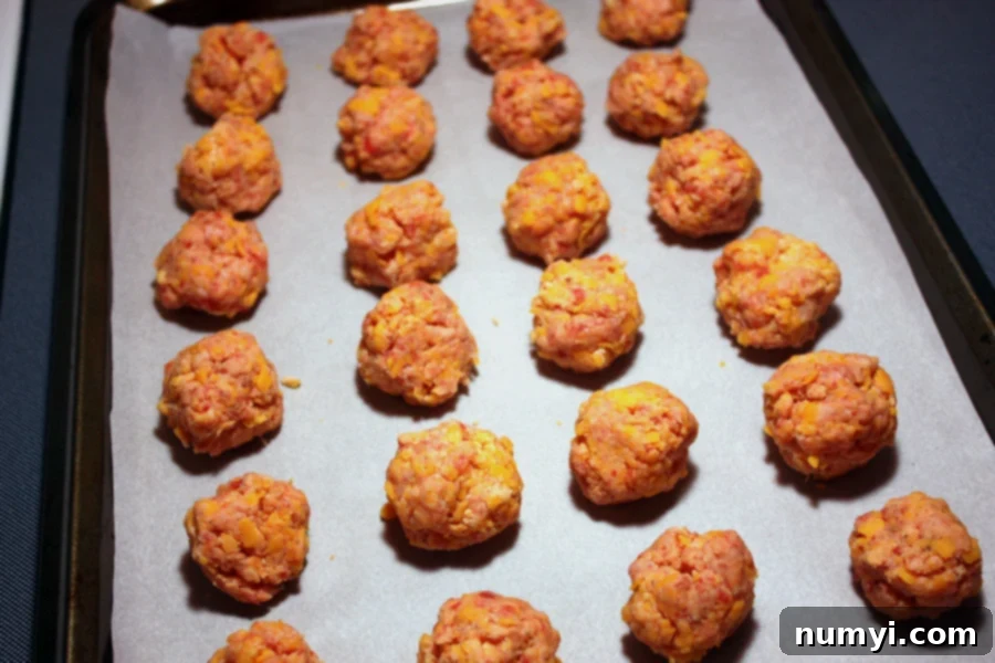 Raw Bisquick sausage balls formed and placed on a parchment paper lined baking sheet.