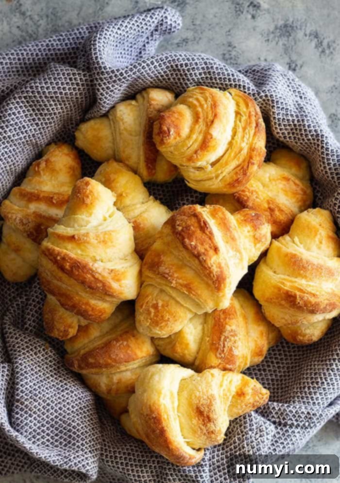 A basket of crescent rolls with a blue towel.
