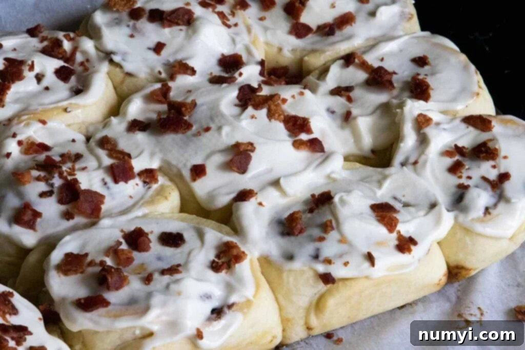 Finished Maple Bacon Cinnamon Rolls, drizzled with maple glaze and sprinkled with bacon, ready to serve.