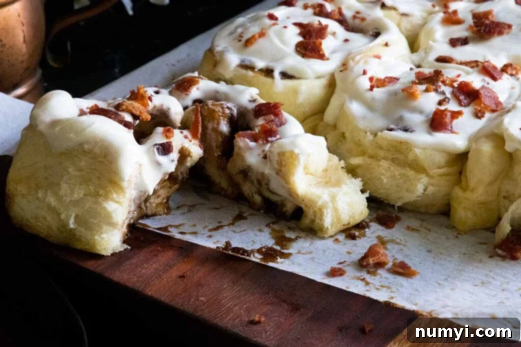 A delicious Maple Bacon Cinnamon Roll cut open, showcasing its fluffy layers and rich filling.