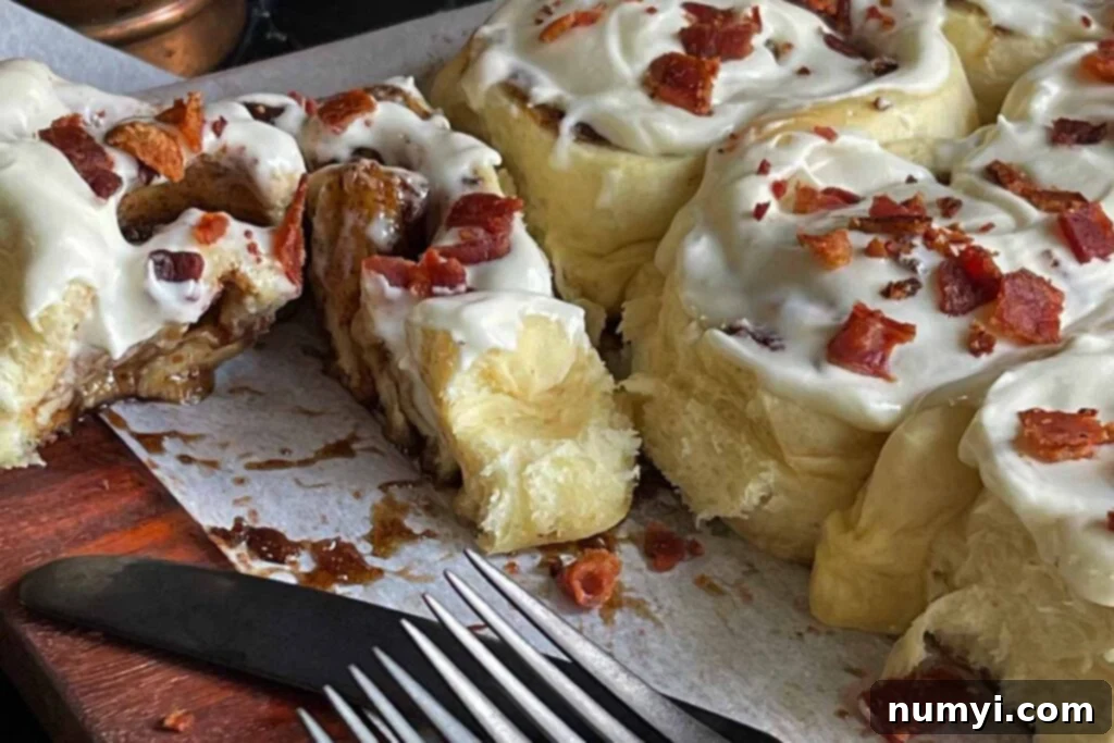 A perfectly sliced Maple Bacon Cinnamon Roll revealing its gooey center and crisp bacon bits.