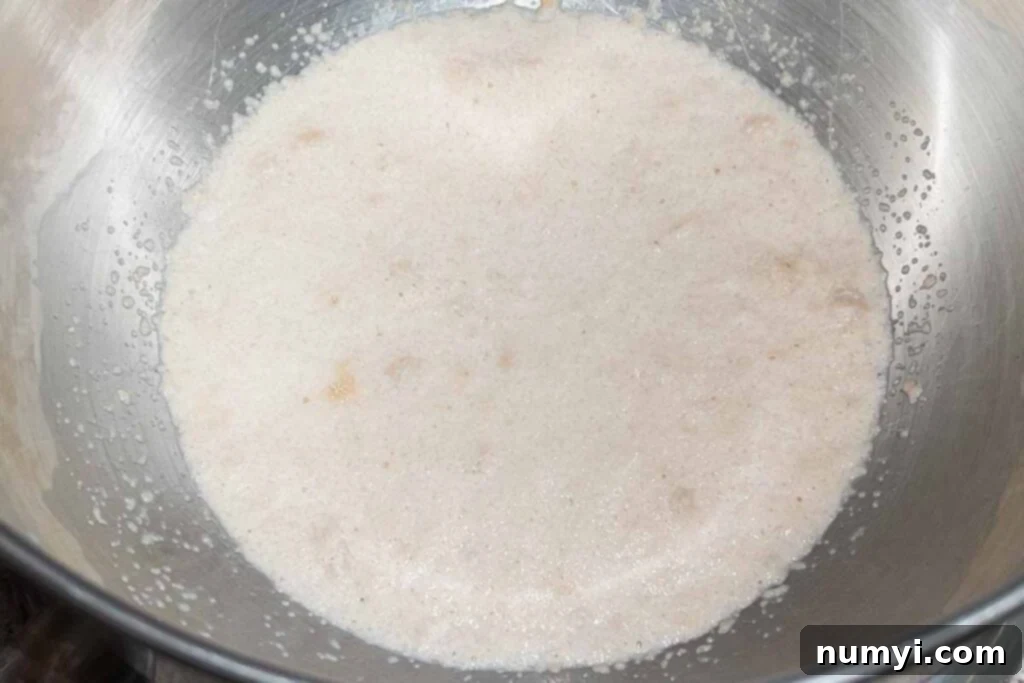 Yeast blooming in a bowl, creating a foamy top layer.