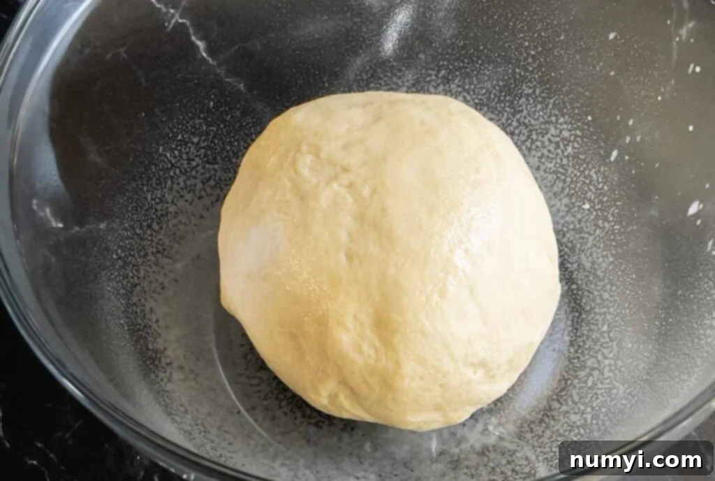 Smooth, well-kneaded dough resting in a glass bowl.