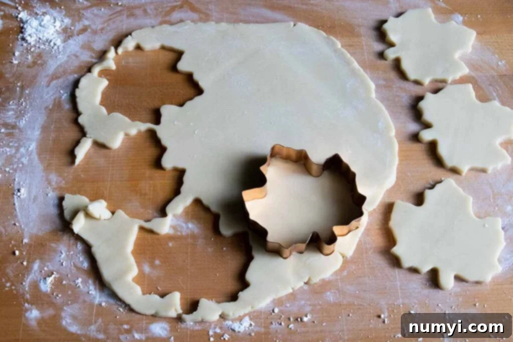 Golden Maple Shortbread Delights 4 Various maple leaf-shaped shortbread cookies cut out on a wooden cutting board, ready for baking.