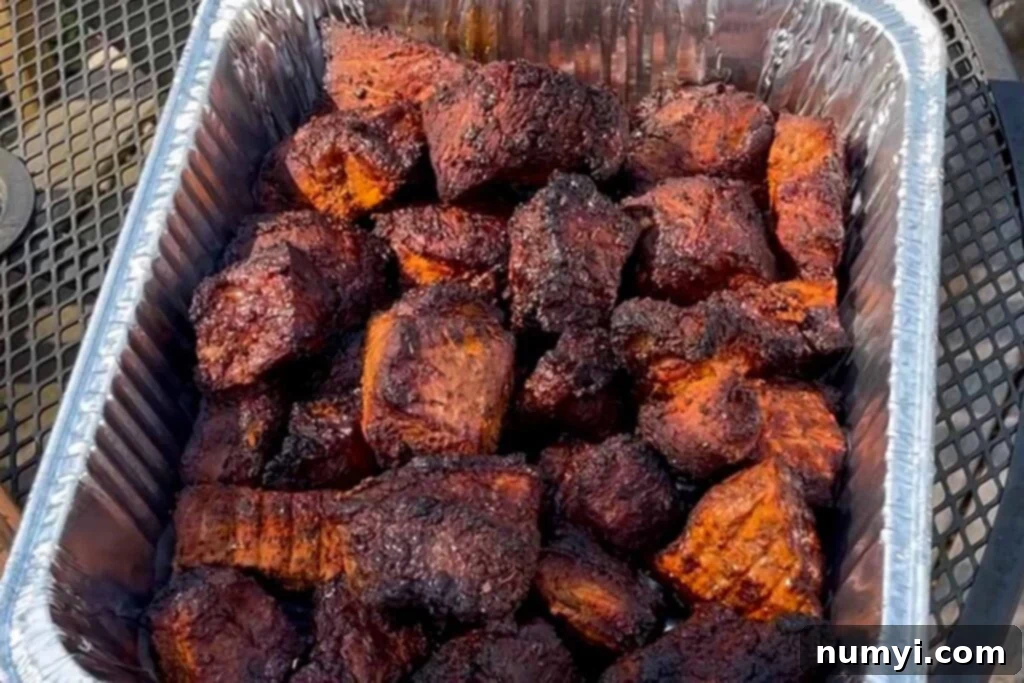 Ultimate Pork Butt Burnt Ends 11 Smoked pork butt burnt ends with a rich, dark bark, removed from the smoker and placed in a disposable aluminum pan, ready for the braising step.