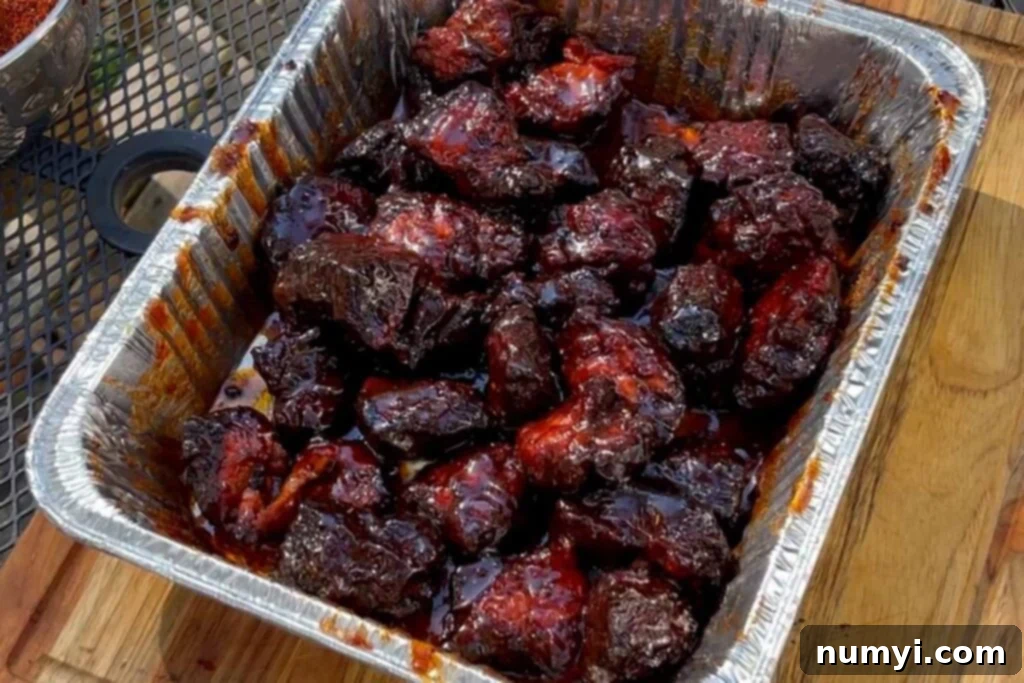 Ultimate Pork Butt Burnt Ends 13 Sauced up pork butt burnt ends, glistening with a sweet and spicy glaze, in a disposable aluminum pan before the final cook.