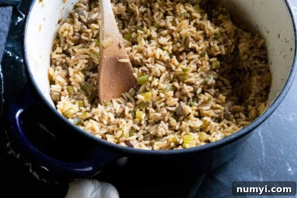 Cajun dirty rice steaming gently in a blue Dutch oven, after cooking, ready for the final step of mixing with the savory meat.