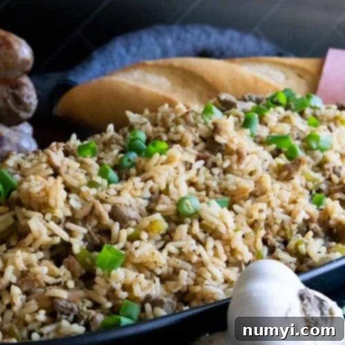 Cajun dirty rice in an oblong dish with a loaf of bread in the background.