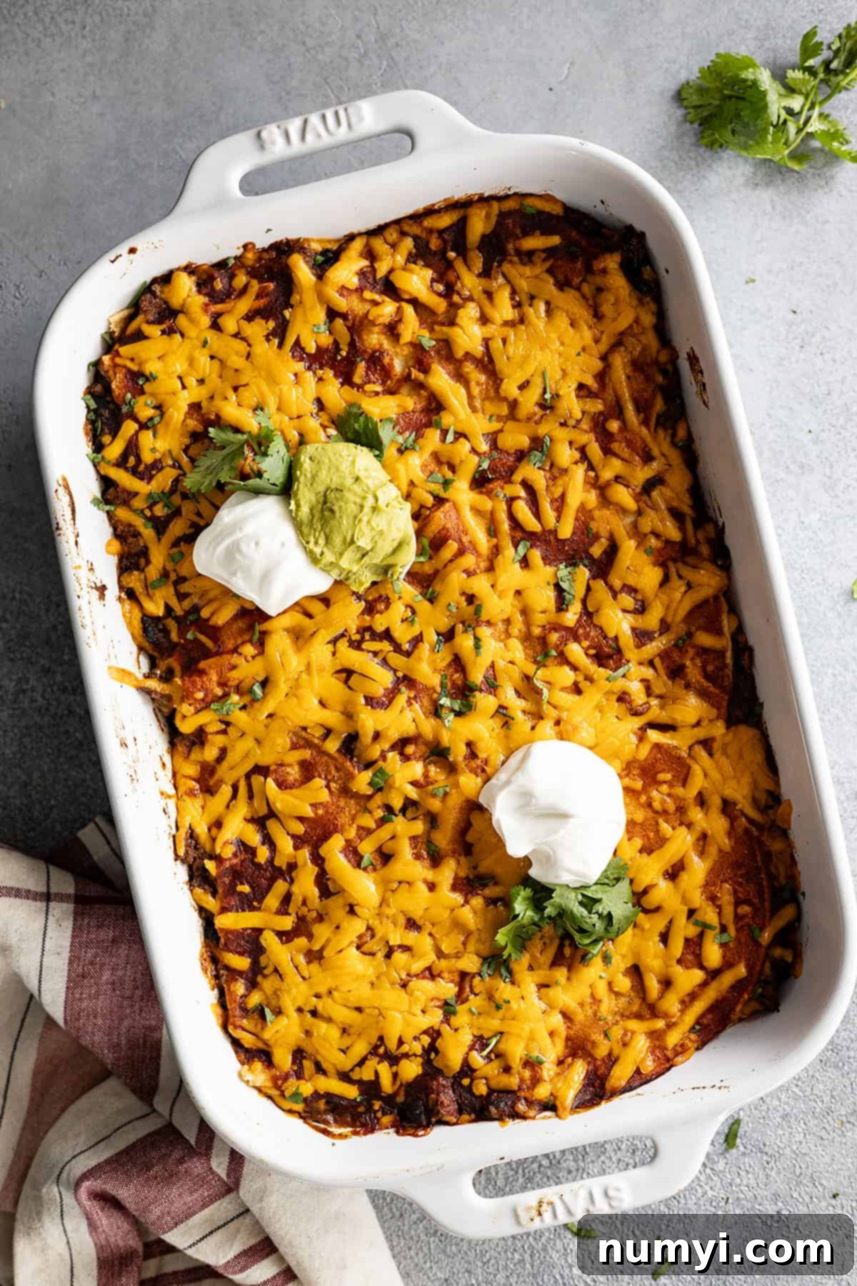 Overhead photo of casserole from the oven and garnished with sour cream, guacamole, and cilantro. 