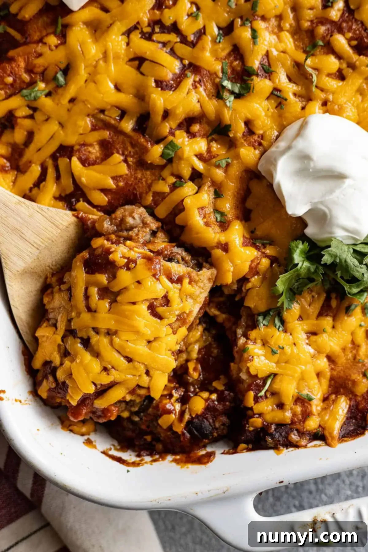 Close up of beef enchilada casserole with a spoon taking a serving out. 