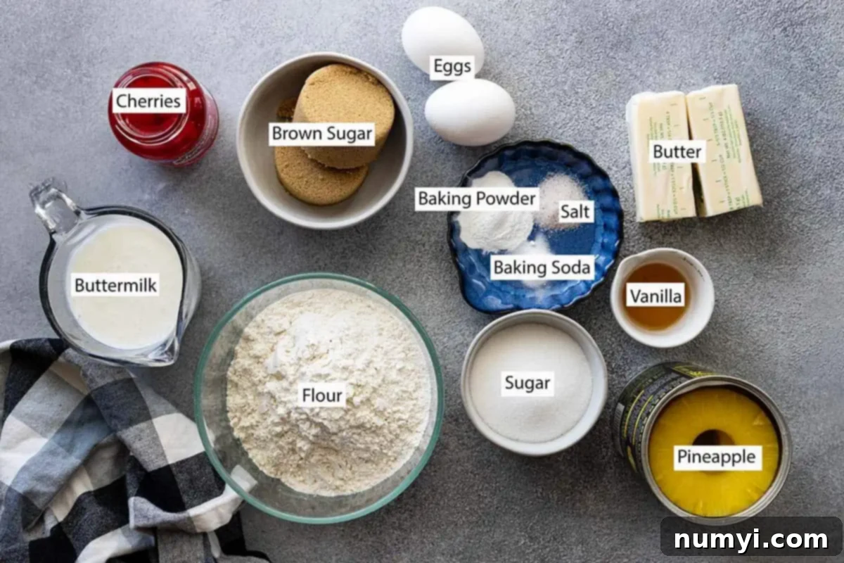 A flat lay of all the essential ingredients for pineapple upside down cake: butter, brown sugar, granulated sugar, canned pineapple slices, maraschino cherries, all-purpose flour, buttermilk, baking powder, baking soda, salt, vanilla extract, and eggs.