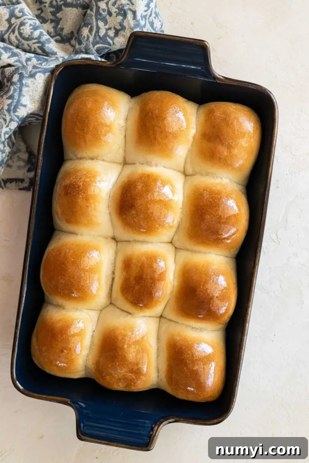Soft Dinner Rolls 2 Overhead picture of dinner rolls out of the oven and brushed with butter. Golden brown and perfectly round, arranged in a baking dish.