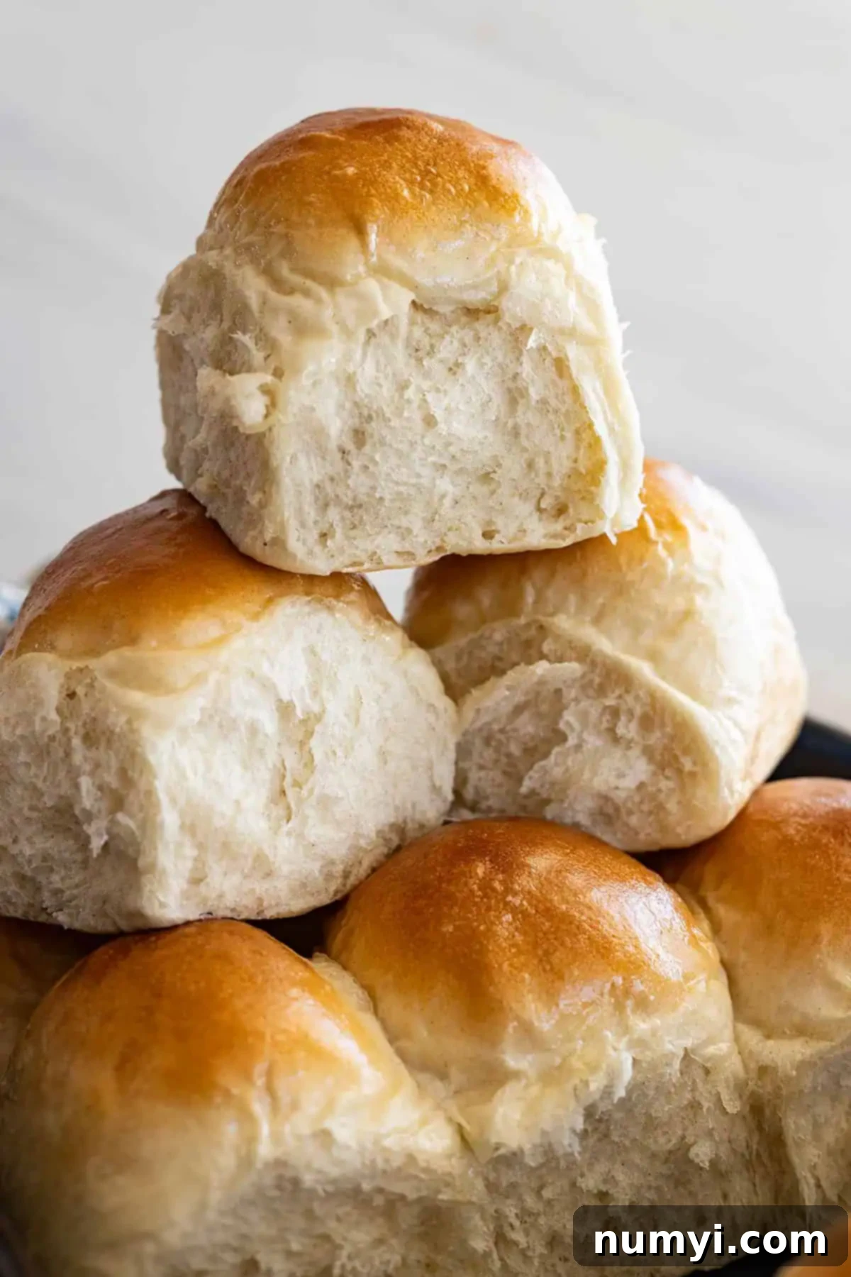 Soft Dinner Rolls 7 Close-up of baked dinner rolls stacked, showing their height and fluffy texture.