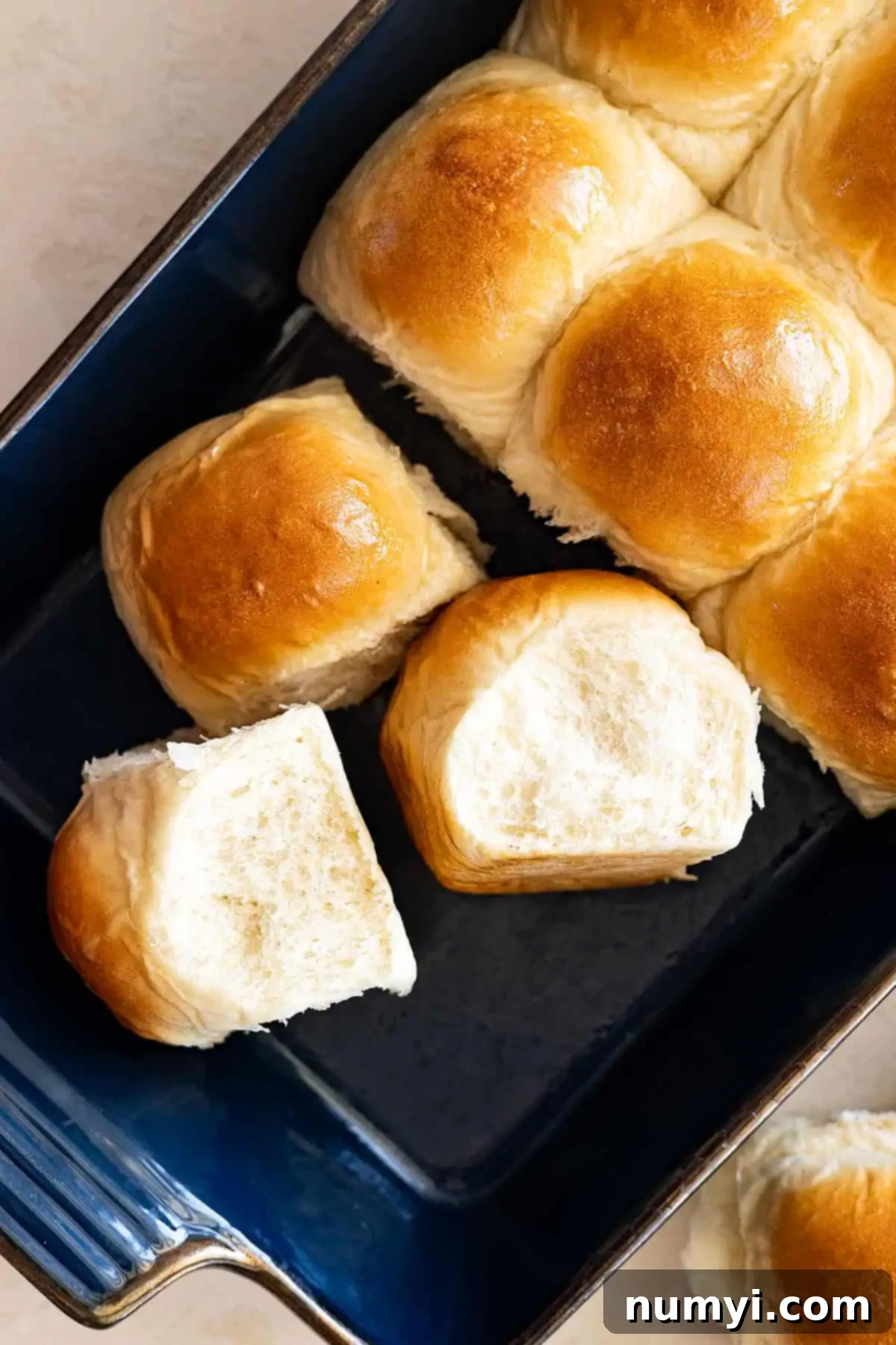 Soft Dinner Rolls 8 Overhead view of golden brown dinner rolls, some turned on their sides to show their tall, fluffy structure.
