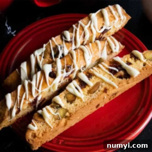 Exquisite White Chocolate Cranberry Pistachio Biscotti 11 Slices of cranberry pistachio biscotti on a dark plate.