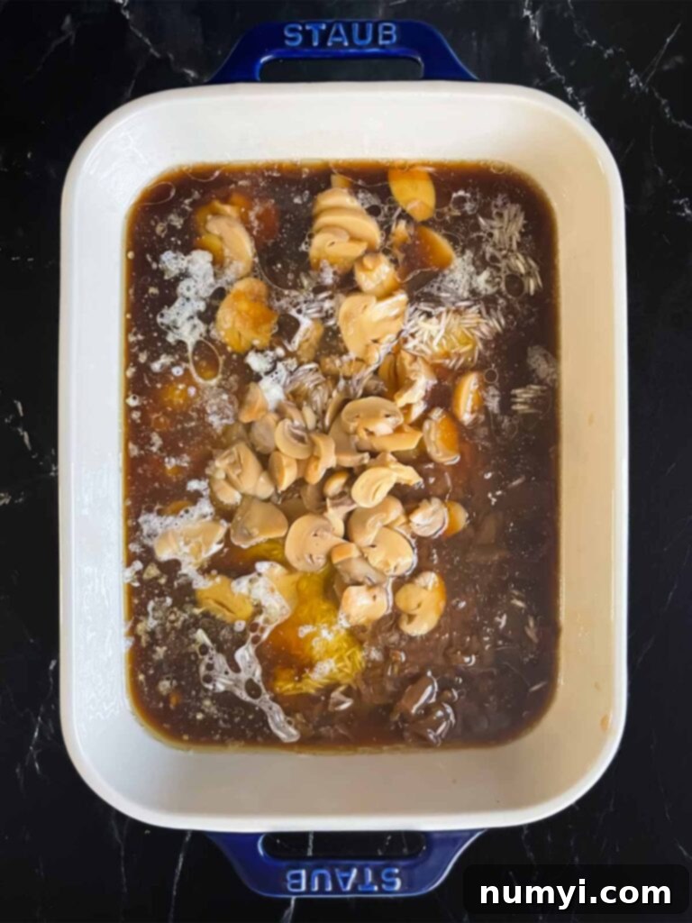All the key ingredients for 'Stick of Butter Rice' – Basmati rice, beef consommé, French onion soup, and sliced mushrooms – stirred together in a casserole dish with melted butter, before baking.