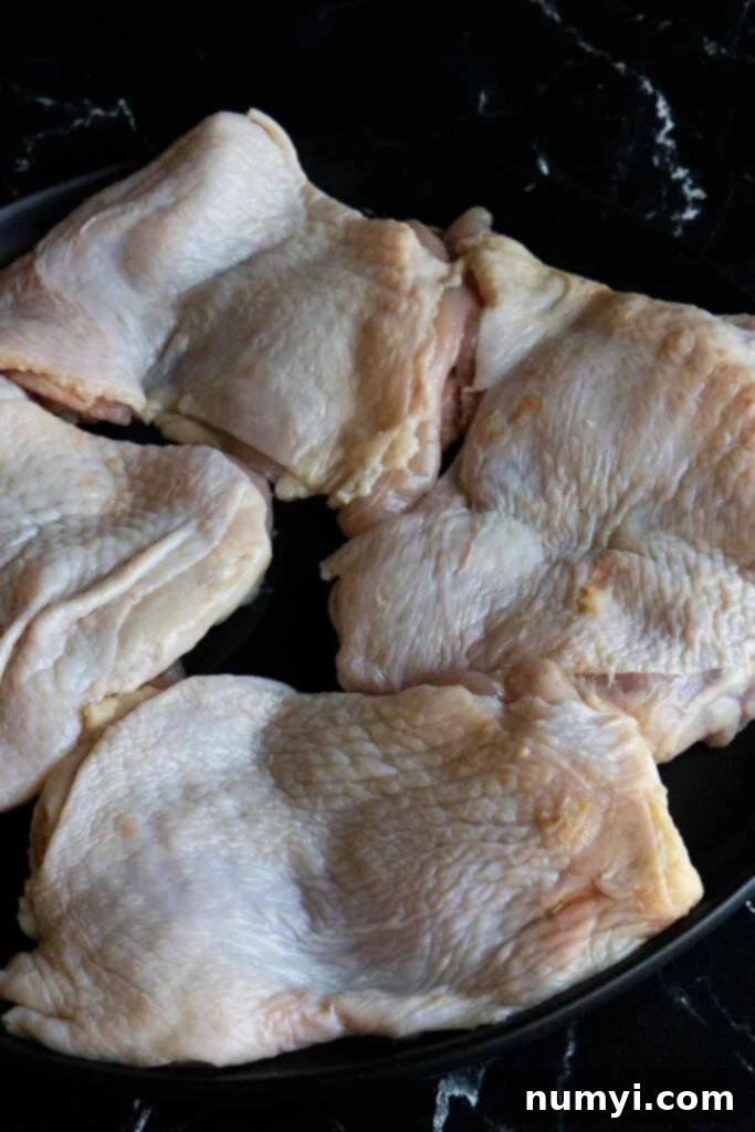 Raw boneless, skin-on chicken thighs, prepared for cooking.
