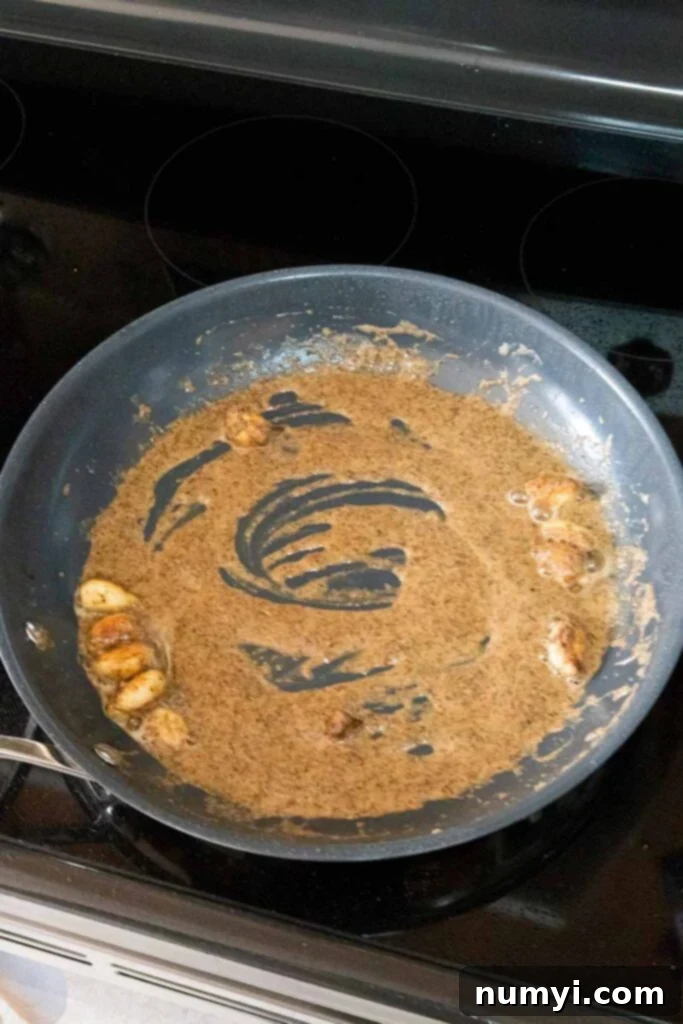 The beginnings of a creamy garlic sauce, with butter, garlic, and spices forming a roux in a skillet.