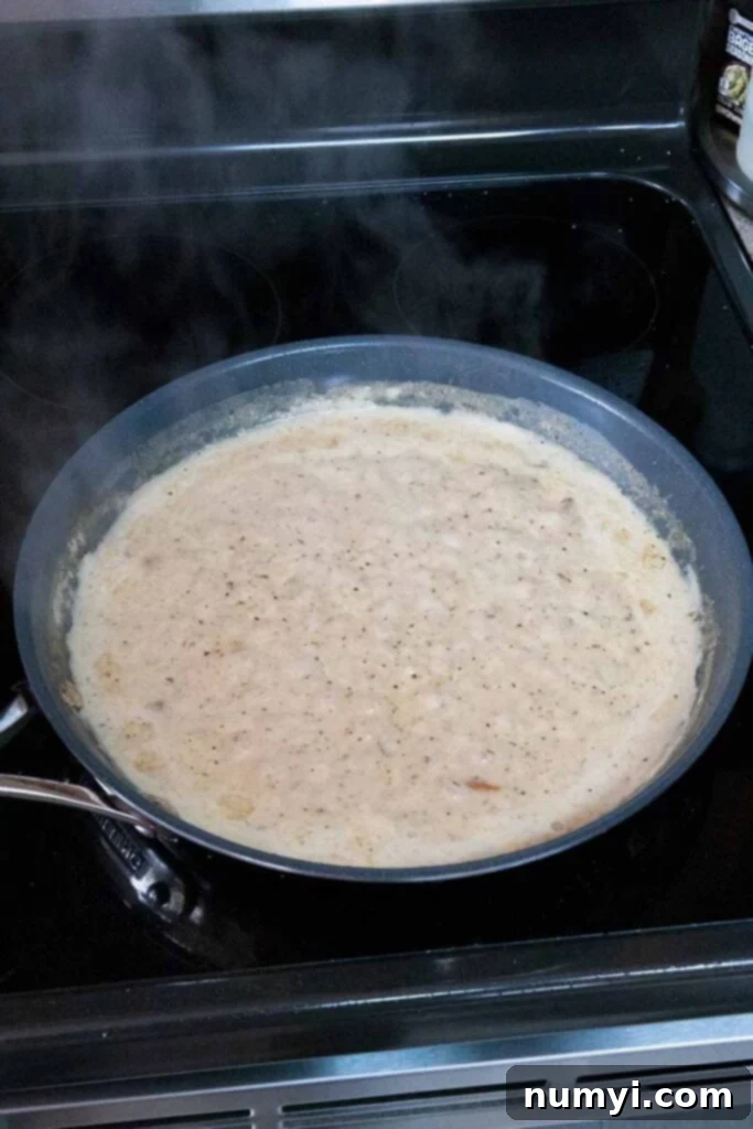 Creamy garlic sauce gently simmering in a skillet.