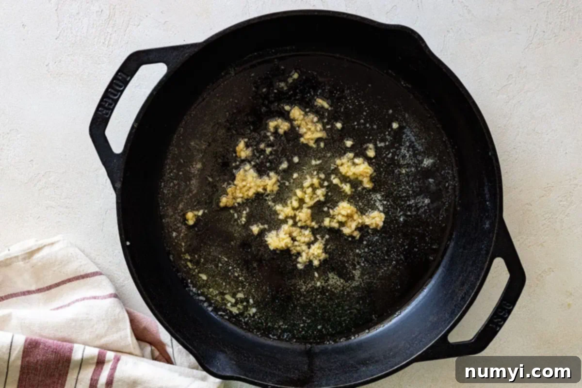 Overhead view of garlic cooking in skillet. 