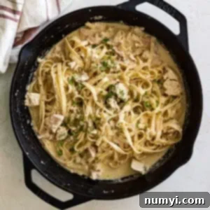 Overhead view of tuna alfredo in a large cast iron skillet garnished with fresh parsley.