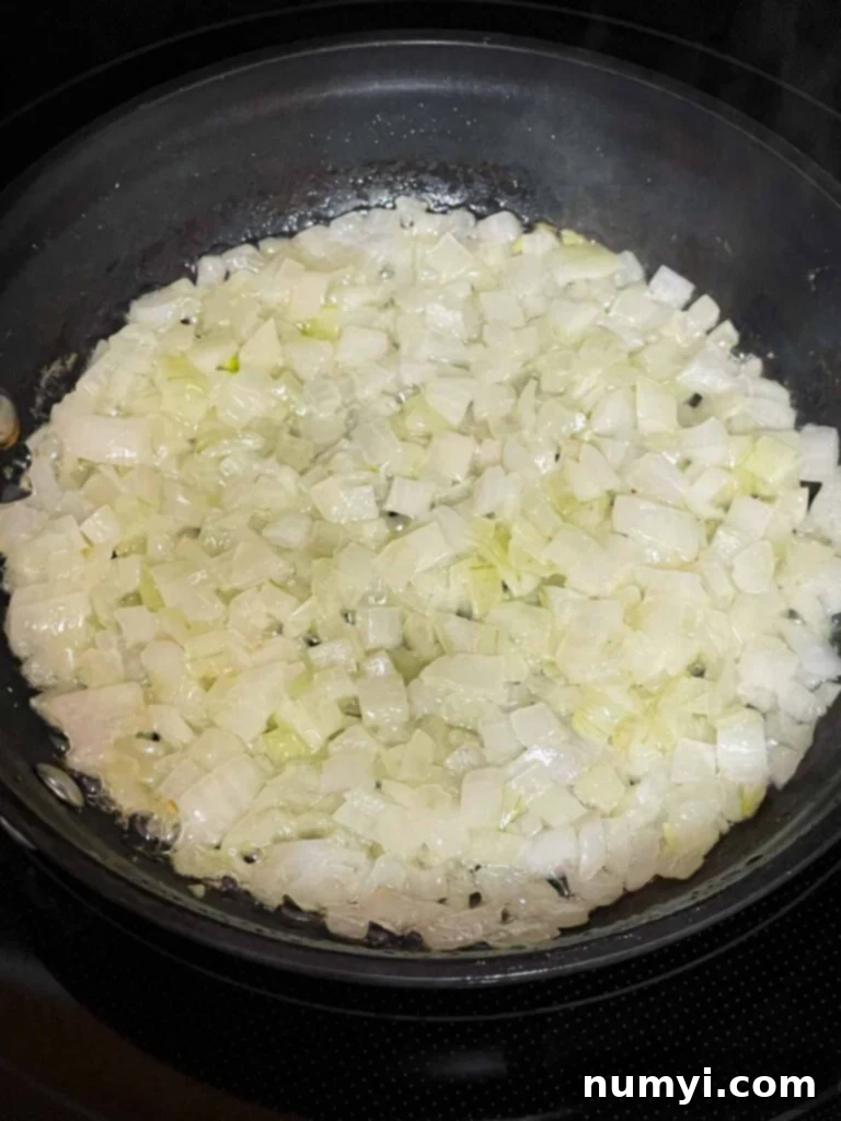 Diced onions for the ham and cheese strata recipe gently sautéing in a small skillet until soft and translucent.