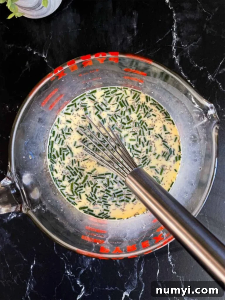 The rich egg mixture for the ham and cheese strata in a large glass measuring bowl, perfectly whisked and ready to be combined with the bread.