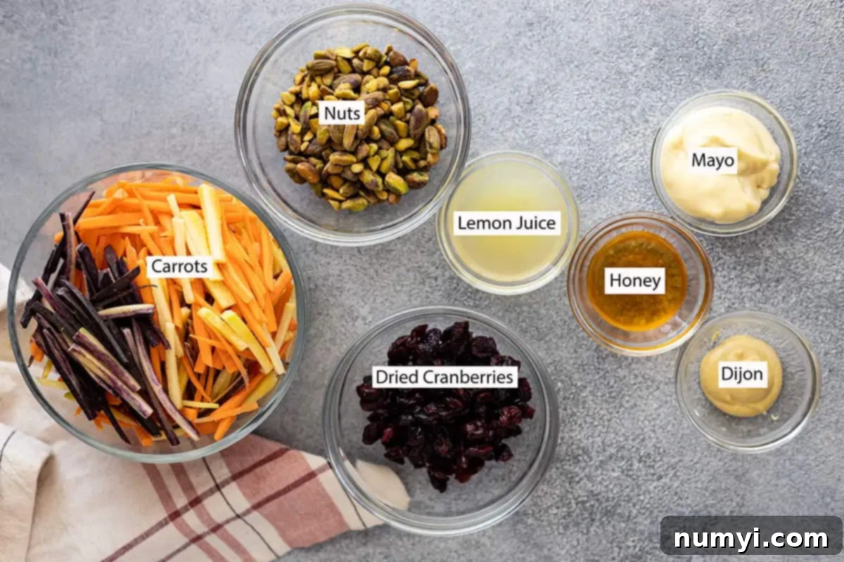 Sunshine Carrot Slaw 3 Close-up of the fresh ingredients laid out on a white surface: vibrant carrots, a bowl of mixed nuts, dried cranberries, a lemon cut in half, a jar of mayonnaise, a squeeze bottle of honey, and a jar of Dijon mustard.